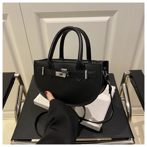 Detail view of black leather saddle bag with silver metal swivel lock and sleek finish