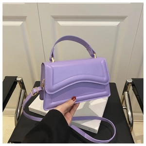Detail view of purple handbag featuring wave-textured leather and gold hardware accents