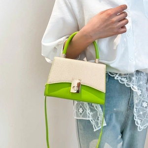 Chic green and white woven contrast handbag with turn-lock clasp shown on a model