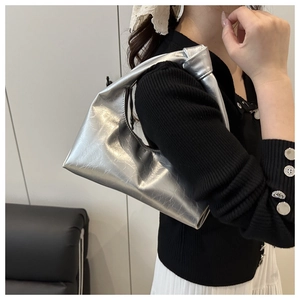 Borsa hobo argento metallizzato con texture, indossata a spalla su un top in maglia nera