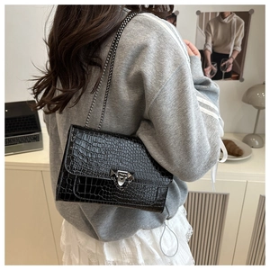 Close-up of black crocodile pattern crossbody bag with silver chain strap and metal lock
