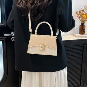 Chic cream leather handbag with woven texture flap and gold lock shown on shoulder