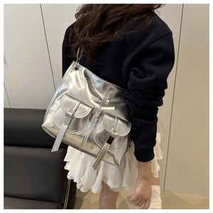 Detail of silver metallic tote bag featuring double front pockets and long zipper pulls