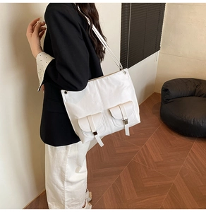 Detail of white PU leather tote bag featuring functional front pockets and buckled flaps