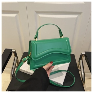 Detail of vivid green faux leather handbag with gold metal buckles and adjustable strap