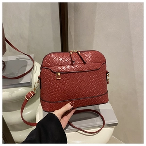 Close-up of wine red woven shell bag featuring gold zippers and adjustable shoulder strap