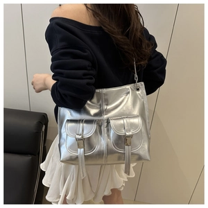 Detail of silver metallic tote bag featuring dual front pockets and industrial buckles
