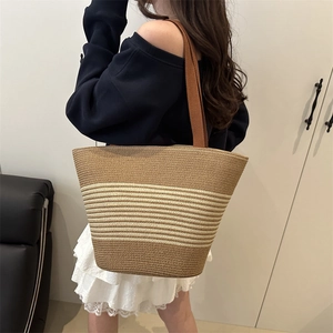 Chic striped woven straw bucket bag with brown straps for elegant summer casual leisure style