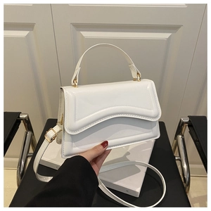 Close-up of a white minimalist square crossbody bag with handle and slim shoulder strap