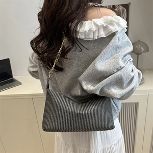 Minimalist black and white woven underarm bag with a slender metal chain strap