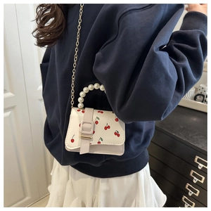 Détail du mini sac blanc à motif cerise avec poignée en perles et chaîne dorée