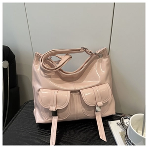Detail of pink glossy patent leather tote bag featuring dual front flap pockets and buckles