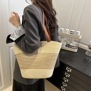 Fashionable striped straw bucket bag with dark brown straps for elegant casual wear