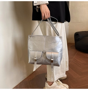 Detail of silver metallic tote bag with front pockets and long decorative straps