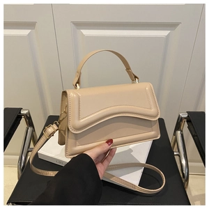 Detail of beige square handbag featuring unique wave texture and shiny leather finish