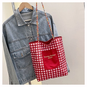 Close-up of red and white checkered tote bag with solid front pocket and woven strap