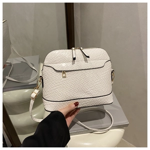 Close-up of white woven texture shell bag with golden zippers and adjustable shoulder strap