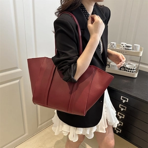 Chic dark red leather tote bag with vertical stripes shown on model's shoulder