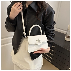 Gros plan d'un sac bandoulière en cuir blanc avec étoile en strass porté par un mannequin