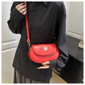 Detail of red leather crossbody bag featuring a silver rhinestone star and adjustable strap