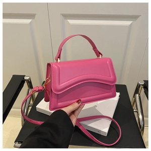 Detail of fuchsia handbag showing unique wavy stitching and polished gold hardware