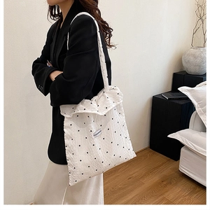 Gros plan du sac cabas blanc à pois avec texture plissée et étiquette de mode tissée