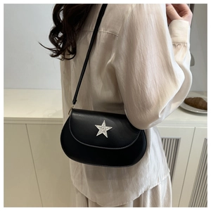 Detail of minimalist black saddle bag featuring a sparkling silver star rhinestone buckle