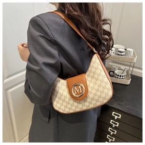 Détail du sac demi-lune montrant le tissu à monogramme M et le fermoir logo doré