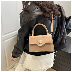 Détail du sac trapèze beige avec boucle étoile en strass et poignée supérieure