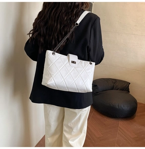 Model wearing a white quilted shoulder bag with chain strap and metal lock detail