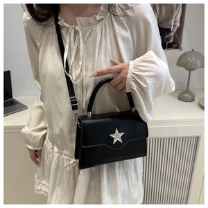 Détail du sac carré noir avec une étoile en strass argentée et finition en similicuir