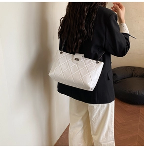 Close-up of white quilted chain shoulder bag with metal turn-lock on a female model