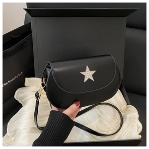 Detail of minimalist black saddle bag with rhinestone star logo in a gift box