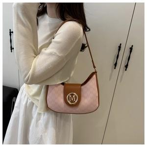 Close-up of pink crescent shoulder bag with metallic M logo and leather strap detail