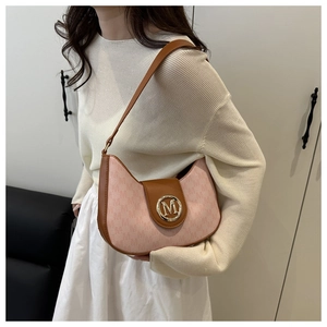 Détail du sac baguette en tissu rose avec bordure en cuir marron et logo M doré