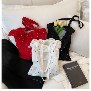 Détails de sacs fourre-tout à fleurs en rouge, blanc et noir avec étiquettes tissées