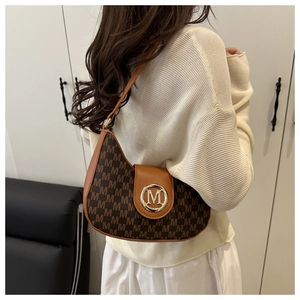 Detail of a brown crescent shoulder bag featuring gold M logo buckle and monogram print