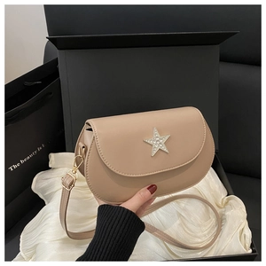 Detail of beige saddle bag with rhinestone star charm and matching leather strap