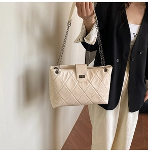 Detail of cream quilted crossbody bag with chain strap and metal turn-lock closure