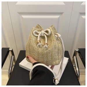 Close-up of beige woven bucket bag featuring drawstring closure and tassel cord handles