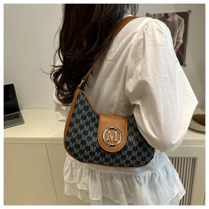 Détail du sac hobo croissant avec motif à lettres M et boucle en métal doré