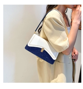 Détail de la texture pailletée bleue et du rabat en cuir blanc du sac à bandoulière