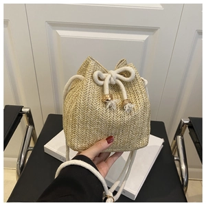 Detailed close-up of woven bucket bag texture with drawstring and gold metal bead tassels
