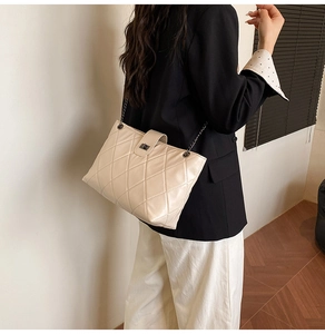Model shot of a beige quilted leather chain bag showing its side profile and metal lock