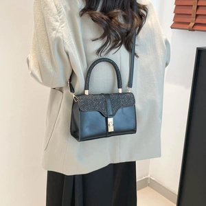 Elegant black leather handbag with glittery sequins worn by a model in casual setting