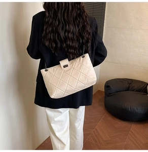 Detail of beige quilted shoulder bag with chain strap and metal swivel lock closure