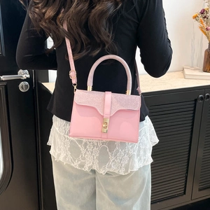 Pink glitter accent flap handbag with gold clasp and adjustable strap in a modern setting