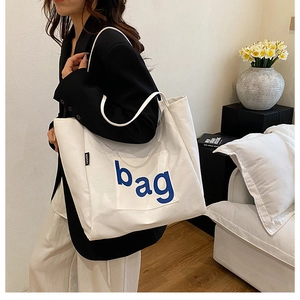 Detail of white canvas tote bag with blue bag print and functional front pocket