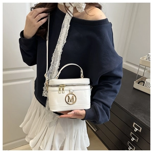 Détail du sac boîte blanc avec logo M doré, double fermeture éclair et ruban dentelle