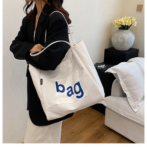 White canvas tote bag with blue bag print shown in a modern lifestyle setting